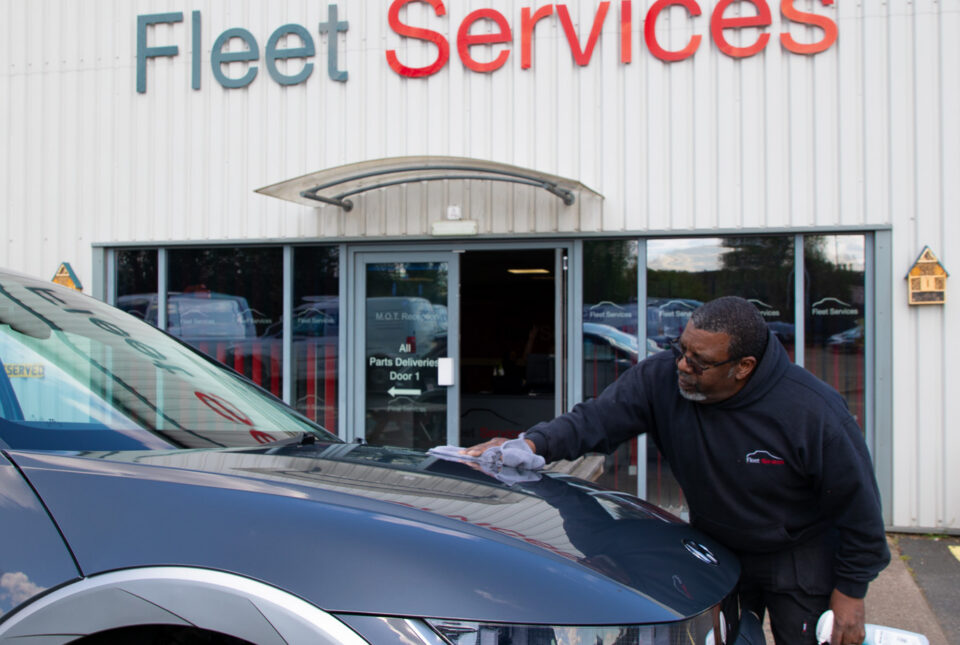 Man polishing a vehicle outside Fleet services signage